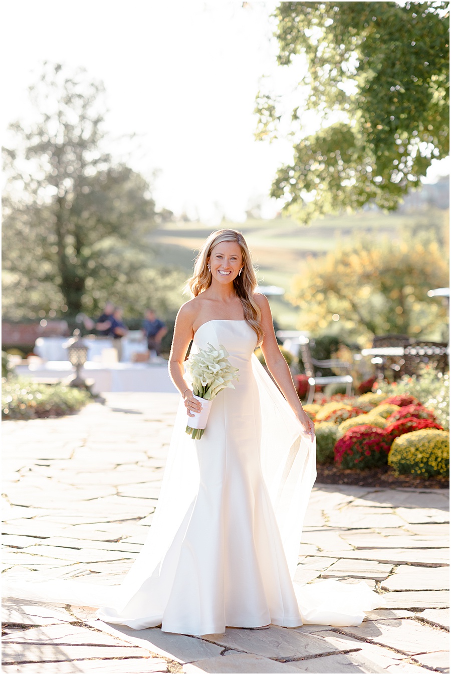 Bridal portrait in historic gardens wearing veil cape holding calle lillies